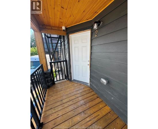 A wooden deck with a white door and a black railing.