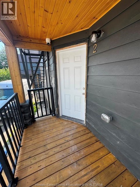 A wooden deck with a white door and a black railing.