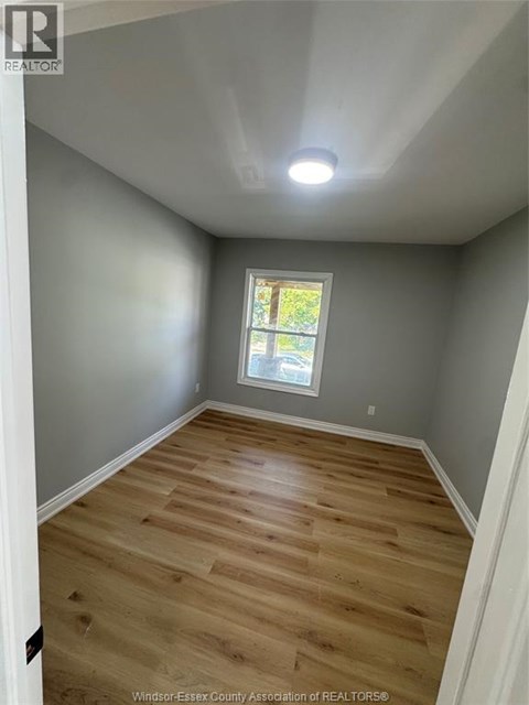 A room with wooden flooring and a window.
