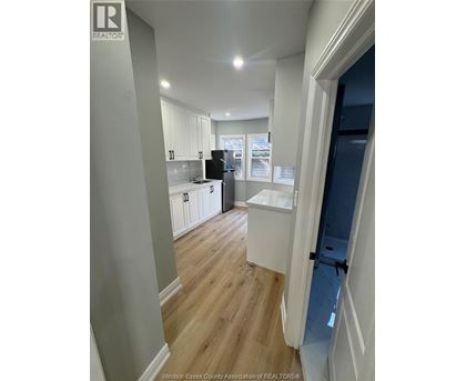 A kitchen with white cabinets and a black fridge.