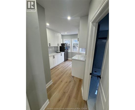 A kitchen with white cabinets and a black fridge.