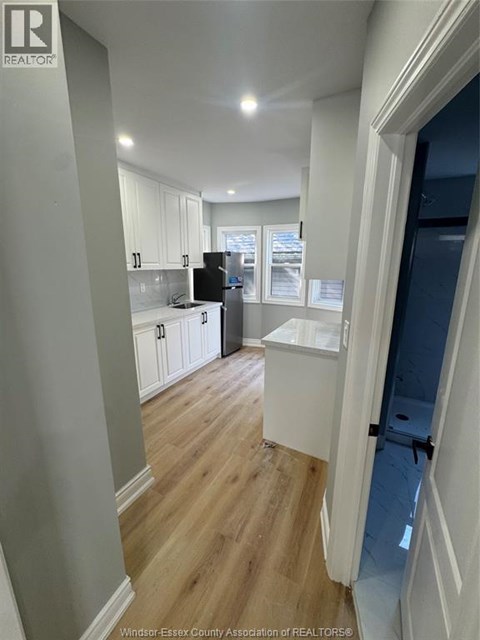 A kitchen with white cabinets and a black fridge.