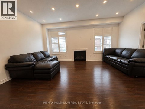 A living room with a black leather couch and a fireplace.