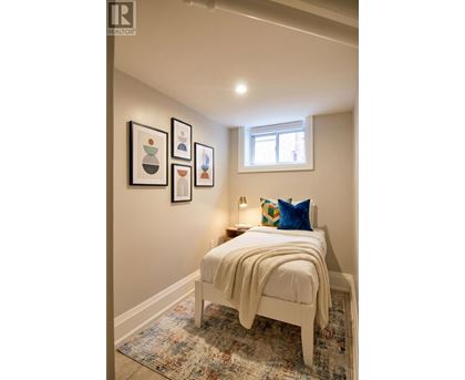A bedroom with a bed, pillow, blanket and pictures on the wall.