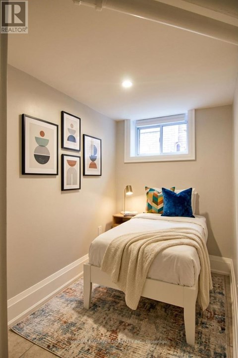 A bedroom with a bed, pillow, blanket and pictures on the wall.