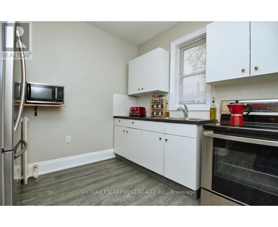 A kitchen with white cabinets and a microwave on the wall.