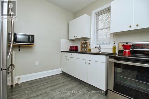 A kitchen with white cabinets and a microwave on the wall.