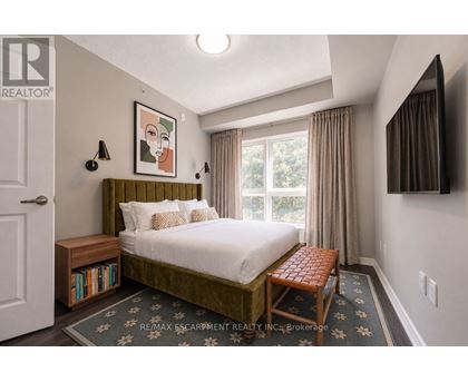 A bedroom with a bed, nightstand, and window.