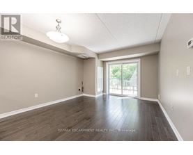 A spacious room with wood flooring and a sliding glass door leading to a balcony.