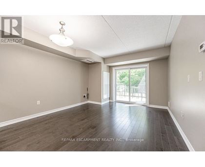 A spacious room with wood flooring and a sliding glass door leading to a balcony.