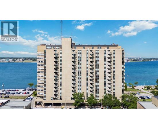 A tall building with a balcony on the top floor overlooks a body of water.