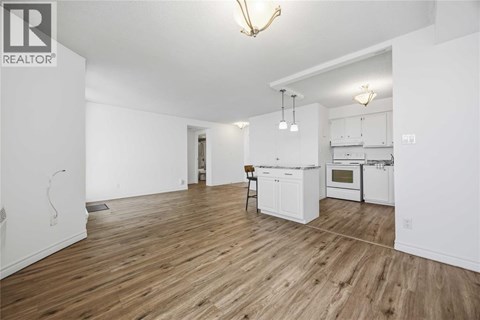 A well-lit, spacious kitchen with white appliances and wooden flooring.