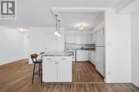 A white kitchen with wood floors and a center island.