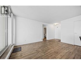 A spacious room with wooden flooring and white walls.