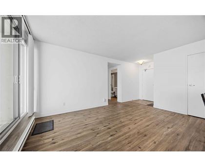 A spacious room with wooden flooring and white walls.