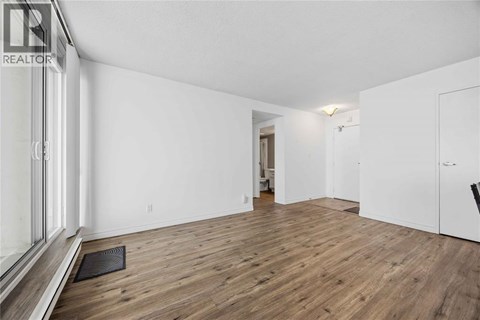 A spacious room with wooden flooring and white walls.
