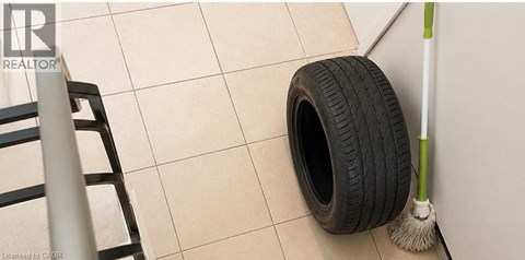 A tire and a broom leaning against a wall.