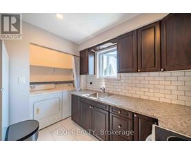 A kitchen with dark wood cabinets and a white sink.