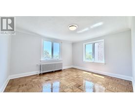 A room with a wooden floor and a window with a view of a tree.