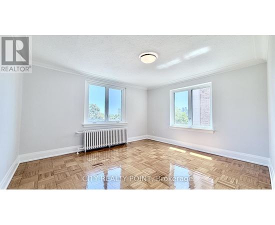 A room with a wooden floor and a window with a view of a tree.