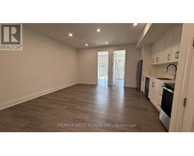 A spacious kitchen with white cabinets and a wooden floor.