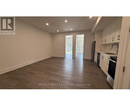 A spacious kitchen with white cabinets and a wooden floor.