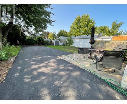 A residential street with a driveway and a lawn chair.
