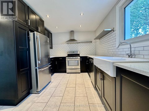 A kitchen with black cabinets and a white tiled backsplash.