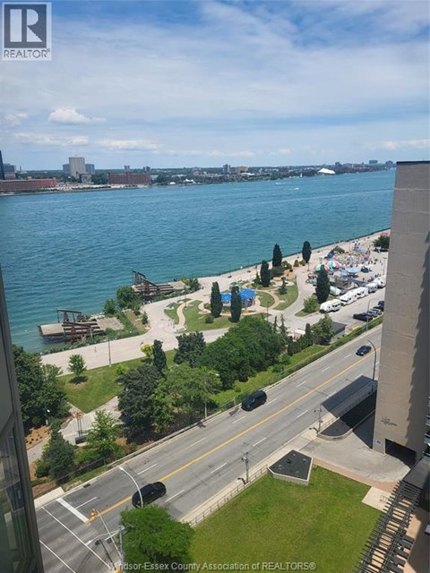 A view from a high-rise building looking out over a waterfront with a park and a road.