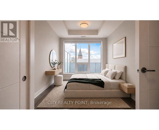 A bedroom with a bed, nightstand, and a window overlooking a cityscape.