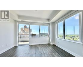 A spacious room with a view of the cityscape through large windows.