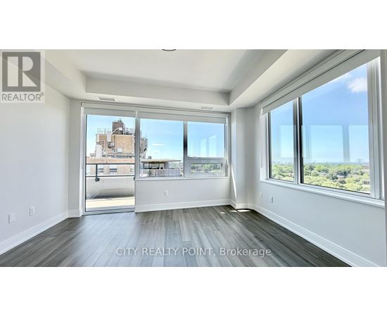 A spacious room with a view of the cityscape through large windows.