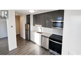 A modern kitchen with stainless steel appliances and wooden flooring.