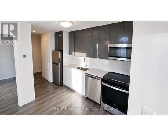 A modern kitchen with stainless steel appliances and wooden flooring.