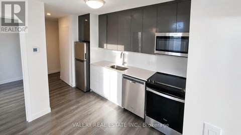 A modern kitchen with stainless steel appliances and wooden flooring.