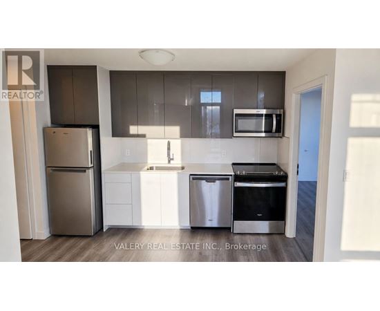 A kitchen with a refrigerator, sink, and stove.