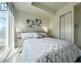 A bedroom with a large bed and a window overlooking a cityscape.