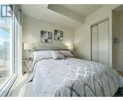A bedroom with a large bed and a window overlooking a cityscape.