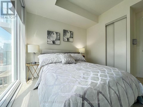 A bedroom with a large bed and a window overlooking a cityscape.