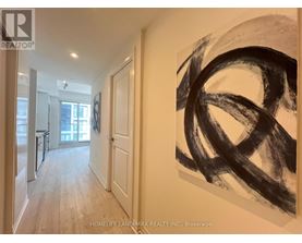 A hallway with a large painting on the wall and a door on the left.