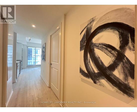 A hallway with a large painting on the wall and a door on the left.