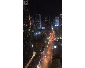 A nighttime city street with cars and buildings.