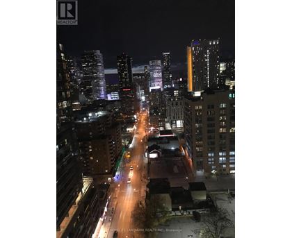 A city street at night with buildings on either side and cars driving down the road.