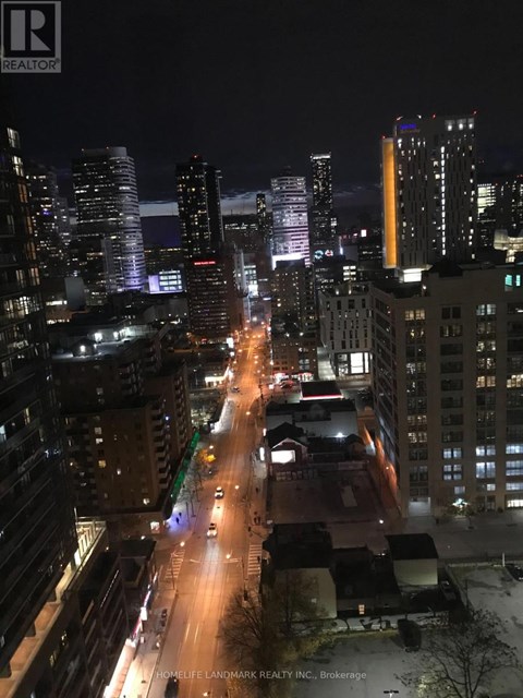 A city street at night with buildings on either side and cars driving down the road.