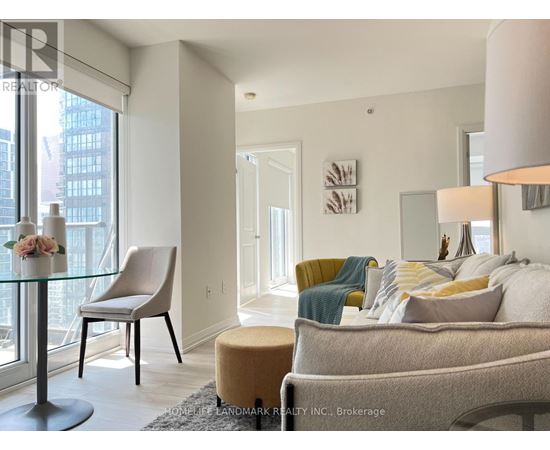 A well-lit living room with a glass table and a yellow chair.