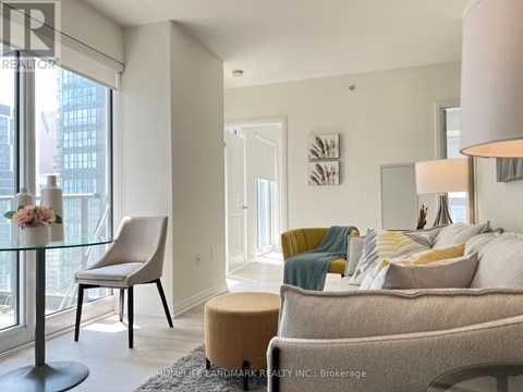 A well-lit living room with a glass table and a yellow chair.