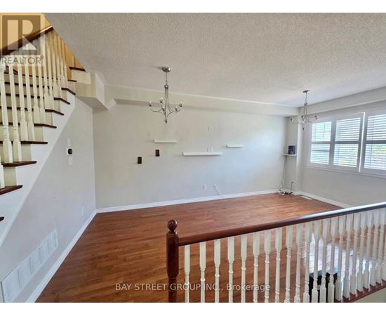 A spacious living room with a staircase on the left and a chandelier hanging from the ceiling.