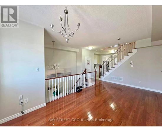 A spacious living room with hardwood floors and a staircase leading to the upper level.
