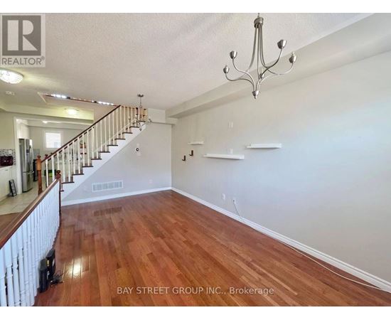 A spacious room with wooden floors and a chandelier.