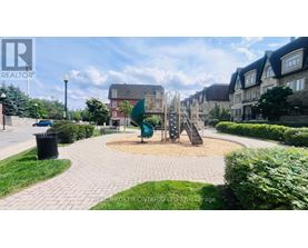 A playground with a slide and a climbing frame in the middle of a paved area.